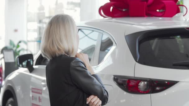 Cliente femminile esaminando nuova automobile in vendita presso concessionaria auto
 - Filmati, video