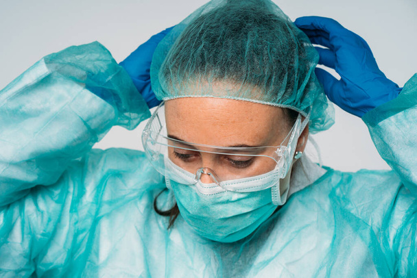 COVID-19 Die Coronavirus-Pandemie: Ärztin setzt medizinische Maske, Brille, Latexhandschuhe und Schutzkleidung gegen das Virus auf - Foto, Bild