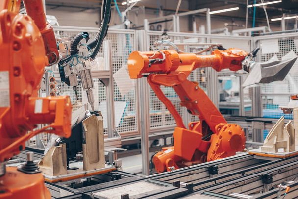 Nahaufnahme automatischer Roboterarme in der Automobilindustrie, Fabrikproduktion von Scheinwerfern für Autos, Industriekonzept - Foto, Bild