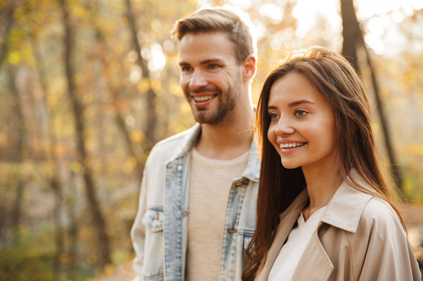 Beautiful smiling young couple walking in the autumn park - Foto, imagen