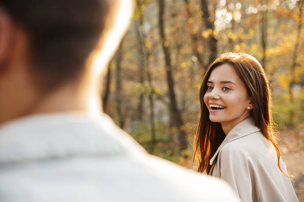 Close up of a beautiful smiling young couple walking in the autumn park - Fotografie, Obrázek