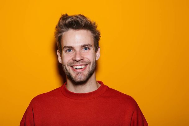 Attractive happy young man wearing pullower standing isolated over yellow background - Fotoğraf, Görsel