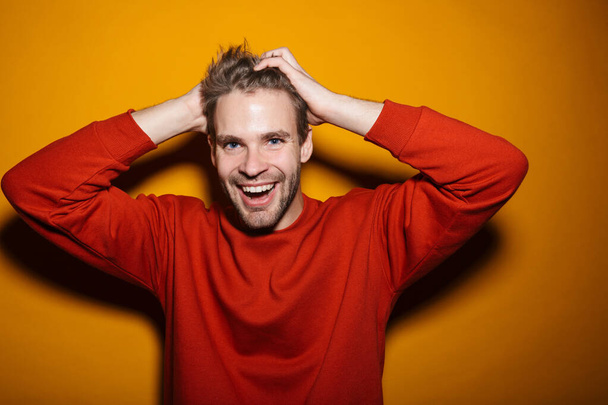 Attractive happy young man wearing pullower standing isolated over yellow background, laughing - Фото, зображення