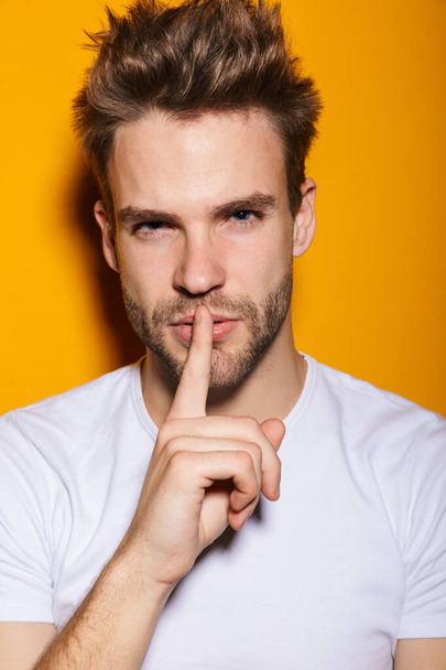 Handsome seductive young man posing isolated over yellow background, looking at camera - Fotografie, Obrázek