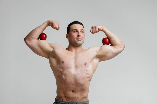 Sporty sexy guy posing on a white background with bright fruits. Diet. Healthy diet - Photo, Image