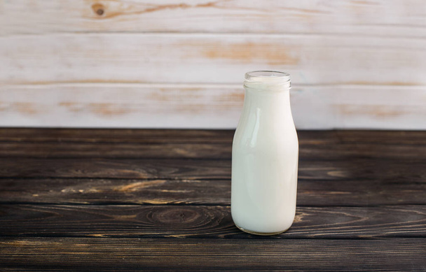 ガラス瓶の中の黒い木の背景に新鮮な牛乳。便利な飲み物 - 写真・画像