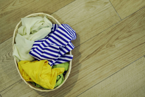 Vista superior Ropa en una cesta de lavandería en el suelo de madera
 - Foto, Imagen