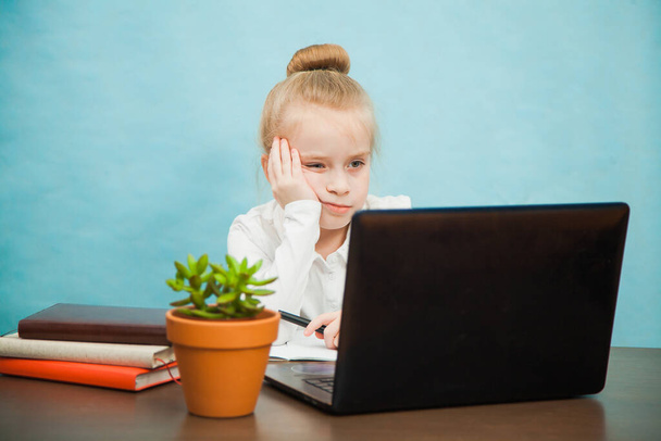 Sad tired elementary student girl homeschooling on laptop online - Photo, image