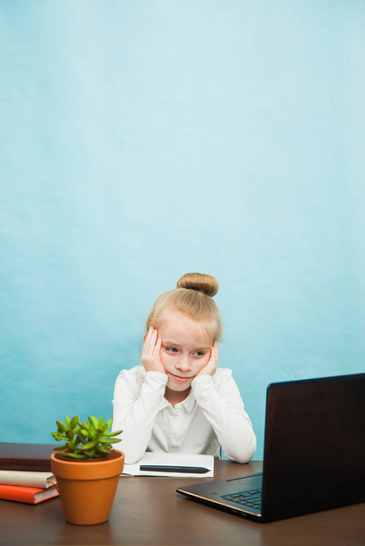 Sad tired elementary student girl homeschooling on laptop online - Photo, Image