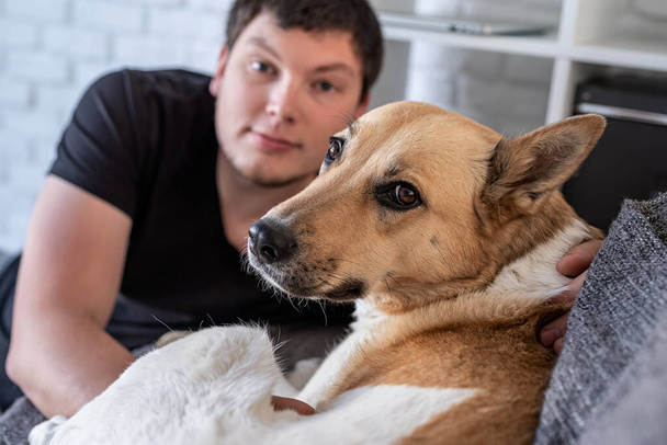Junger Mann sitzt mit Hund zu Hause - Foto, Bild