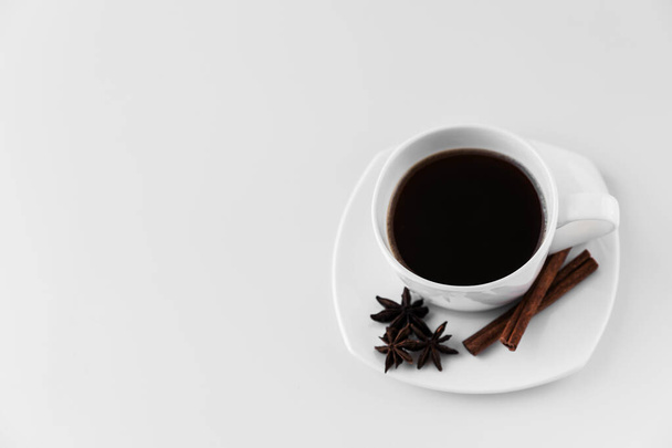 Белая чашка с кофе и блюдцем, с тремя звездочками аниса и палочками каймона на белом фоне. Хорошая идея для меню или знак ресторана или кафе, кафетерий
 - Фото, изображение
