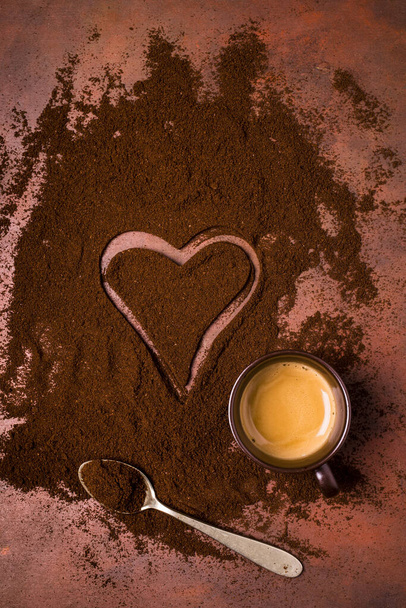 una tazza di espresso cremoso, una pila di caffè macinato con un disegno di un cuore
 - Foto, immagini