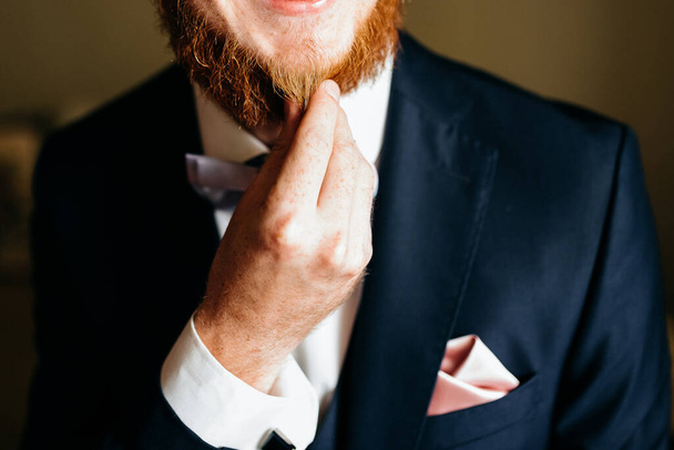 Обрезанный вид красивого мужчины, трогающего свою рыжую бороду
 - Фото, изображение