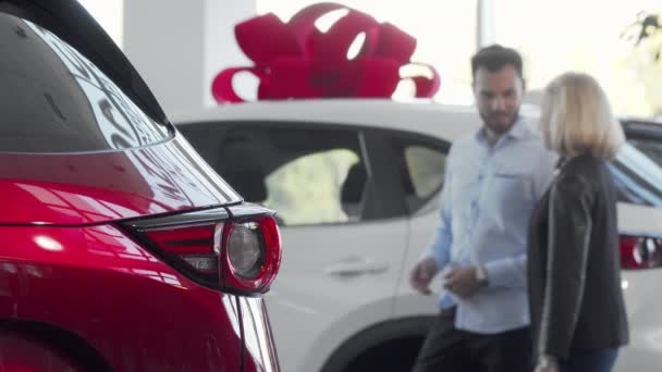 Kochająca się para wybiera samochód do zakupu w salonie samochodowym - Materiał filmowy, wideo
