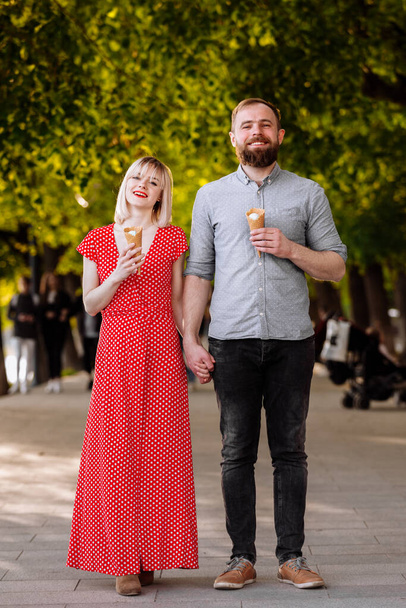 Couple hugging and eating ice cream on street. Tourist couple sharing ice cream outdoors and smiling. A picture of a lovely couple eating ice-cream - Fotografie, Obrázek