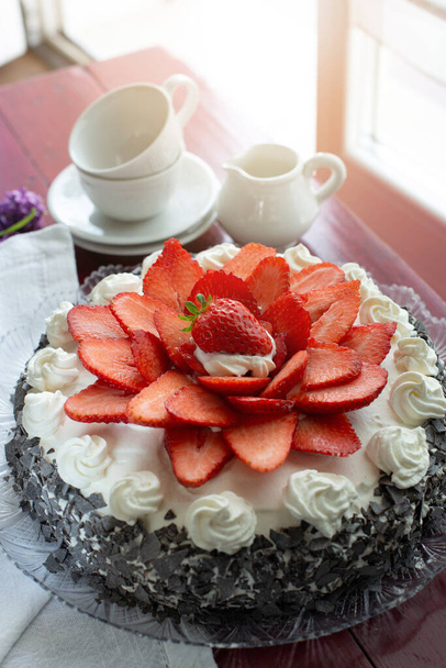 Домашний торт с бисквитом и сливками с молочными сливками, фаршированными клубникой на тарелке
 - Фото, изображение