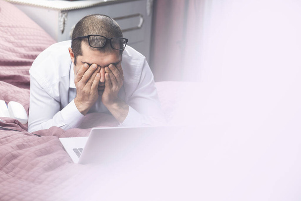 Νεαρός κουρασμένος επιχειρηματίας τρίβει τα μάτια του μετά τη δουλειά - Φωτογραφία, εικόνα