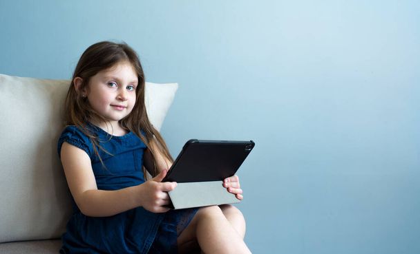 Ребенок использует планшет для самообразования во время карантина. Девочка учится онлайн. Ребенок ищет информацию в Интернете
. - Фото, изображение