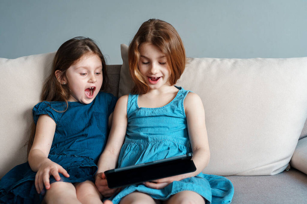 Los niños usan la tableta para autoeducación durante la cuarentena. Las niñas estudian en línea. Los niños buscan información en Internet
. - Foto, imagen