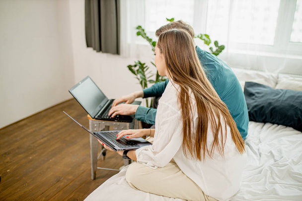 joven pareja caucásica utilizar el ordenador portátil, trabajo en casa, ocupado con su propio negocio
 - Foto, Imagen