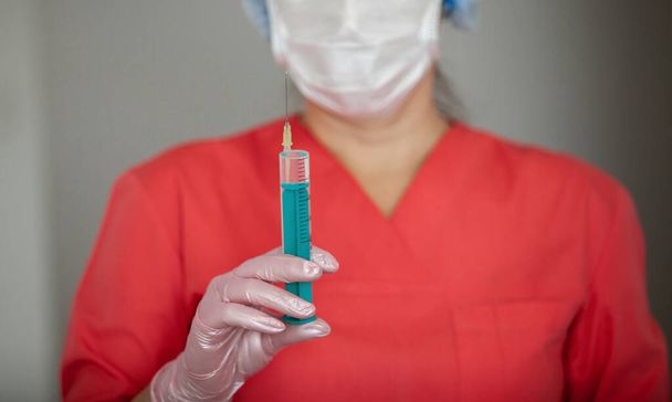 Female doctor in gloves and mask, holds a syringe for injection. - Foto, Bild