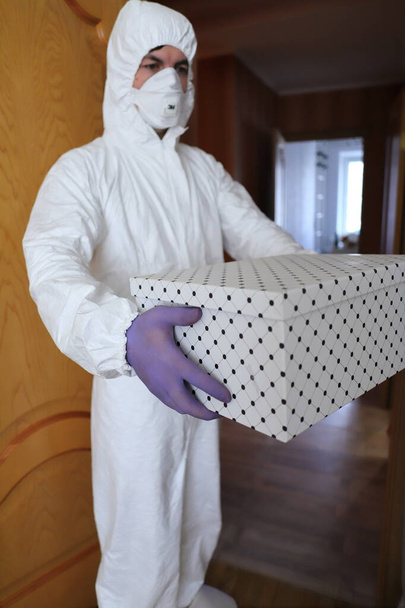 delivery of food and basic necessities to the home in a quarantined environment in a protective suit and gloves - Foto, Imagen