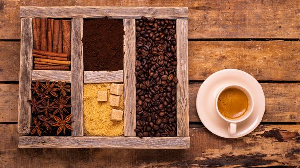 na rustykalnym drewnianym stole z widokiem na góry, filiżanką espresso, drewnianym pojemnikiem z różnymi przyprawami, cukrem surowym i ziarnem kawy - Zdjęcie, obraz