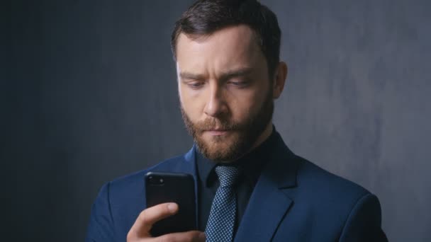 Male professional holding smartphone reading message. Serious businessman using helpful mobile apps for business time management organization - Filmmaterial, Video