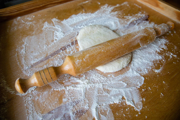 Rouleau brun avec petite pâte blanche et farine de blé sur fond de plan de travail en dalle de bois
 - Photo, image