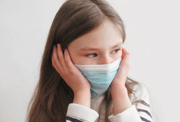 Sad girl in mask at home on quarantine. - Foto, imagen