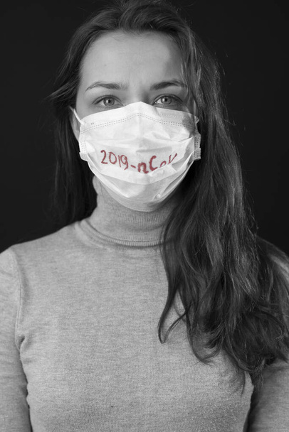 Porträt einer Frau mit Angst vor Coronavirus in medizinischer Maske mit 2019-ncov geschrieben - Foto, Bild