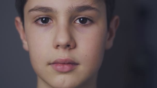 close-up gezicht van schattig jongetje van 10 leeftijden kijken naar camera thuis in de avond - Video