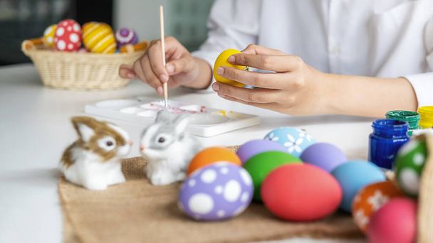 Gelukkig Aziatische vrouw schilderen eieren voor Pasen thuis. Familie bereidt Pasen voor. - Foto, afbeelding