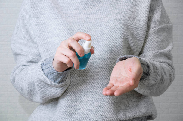 Antibacterial disinfectant spray in the hands of a caucasian woman in a plastic bottle. Treatment for bacteria and viruses. - Photo, Image