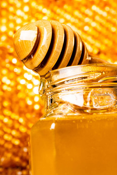 o mel flui suavemente da concha de madeira em primeiro plano
 - Foto, Imagem