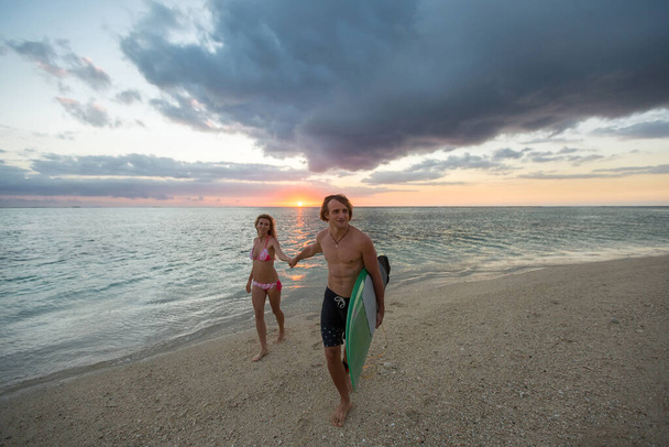 Uomo e donna con tavole da surf al tramonto
. - Foto, immagini