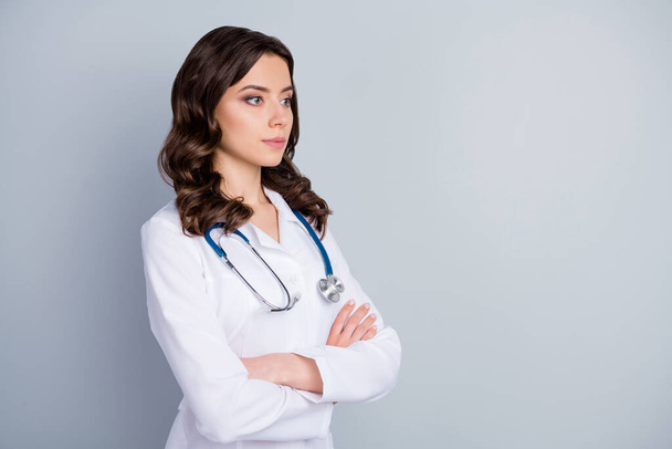 Profile photo of attractive family doc lady patients consultation not smiling virology clinic arms crossed look empty space wear lab coat stethoscope isolated grey color background - Photo, image