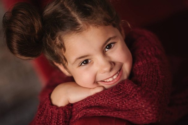 portrait of a smiling little girl in red sweater - Фото, изображение