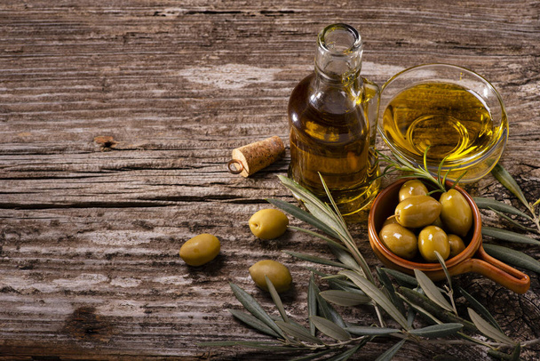 au premier plan, sur la table rustique en bois, bols aux olives vertes, branche d'olivier et huile d'olive extra vierge
 - Photo, image