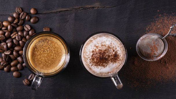 vista superior, primer plano, sobre el fondo de madera oscura, algunos tipos de bebidas a base de espresso, latte macchiato y capuchino con una pizca de cacao en polvo
. - Foto, imagen