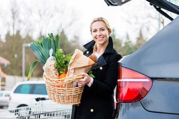 Frau lädt Lebensmittel nach Einkauf in Kofferraum ihres Autos - Foto, Bild