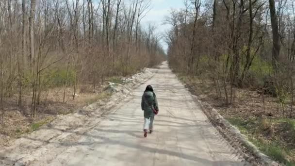Mädchen beim Spazierengehen im Frühlingswald. Copter beobachtet das Mädchen von hinten. - Filmmaterial, Video
