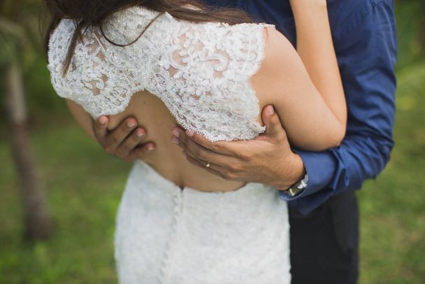 the bride and groom embrace close-up against a background of green grass. - Photo, Image
