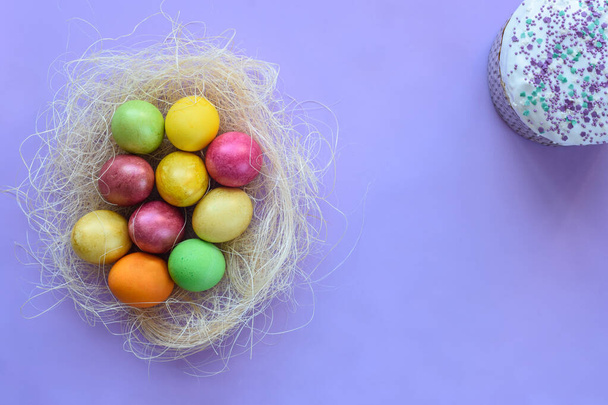 Huevos de Pascua sobre fondo morado, junto al pastel de Pascua
 - Foto, Imagen