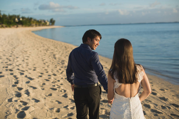 наречений і наречений, що гуляють пляжем Маврикію.. - Фото, зображення