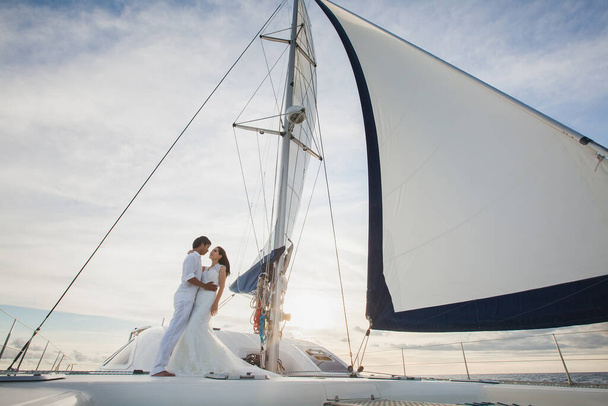 Beautiful wedding couple bride and groom on yacht at wedding day outdoors in the sea. Happy marriage couple kissing on boat in ocean. Stylish Marine wedding. - Fotografie, Obrázek
