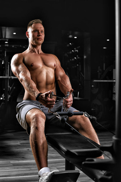 Όμορφος bodybuilder κάνει βαριά άσκηση βάρους για την πλάτη σε έναν προσομοιωτή. Αθλητικό σώμα, προετοιμασία για την καλοκαιρινή περίοδο. Κίνητρο ικανότητας. Αντιγραφή χώρου, sport banner - Φωτογραφία, εικόνα