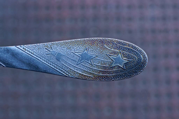 grauer Metallgabelgriff mit Muster auf braunem Hintergrund - Foto, Bild