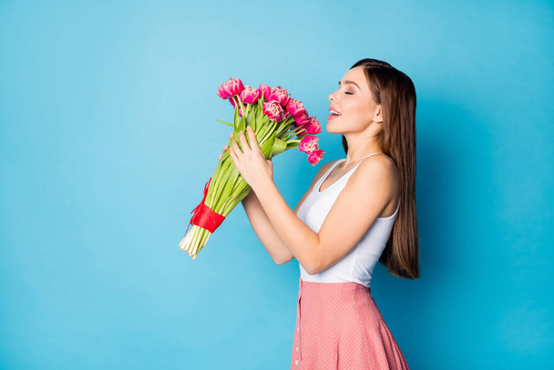 Profile side photo of cheerful pretty attractive girl enjoy her 14-february gift fresh natural tulips bouquet smell wear style trendy singlet isolated over blue color background - Foto, afbeelding