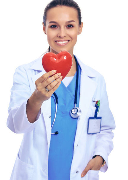 Positive female doctor standing with stethoscope and red heart symbol isolated - Φωτογραφία, εικόνα